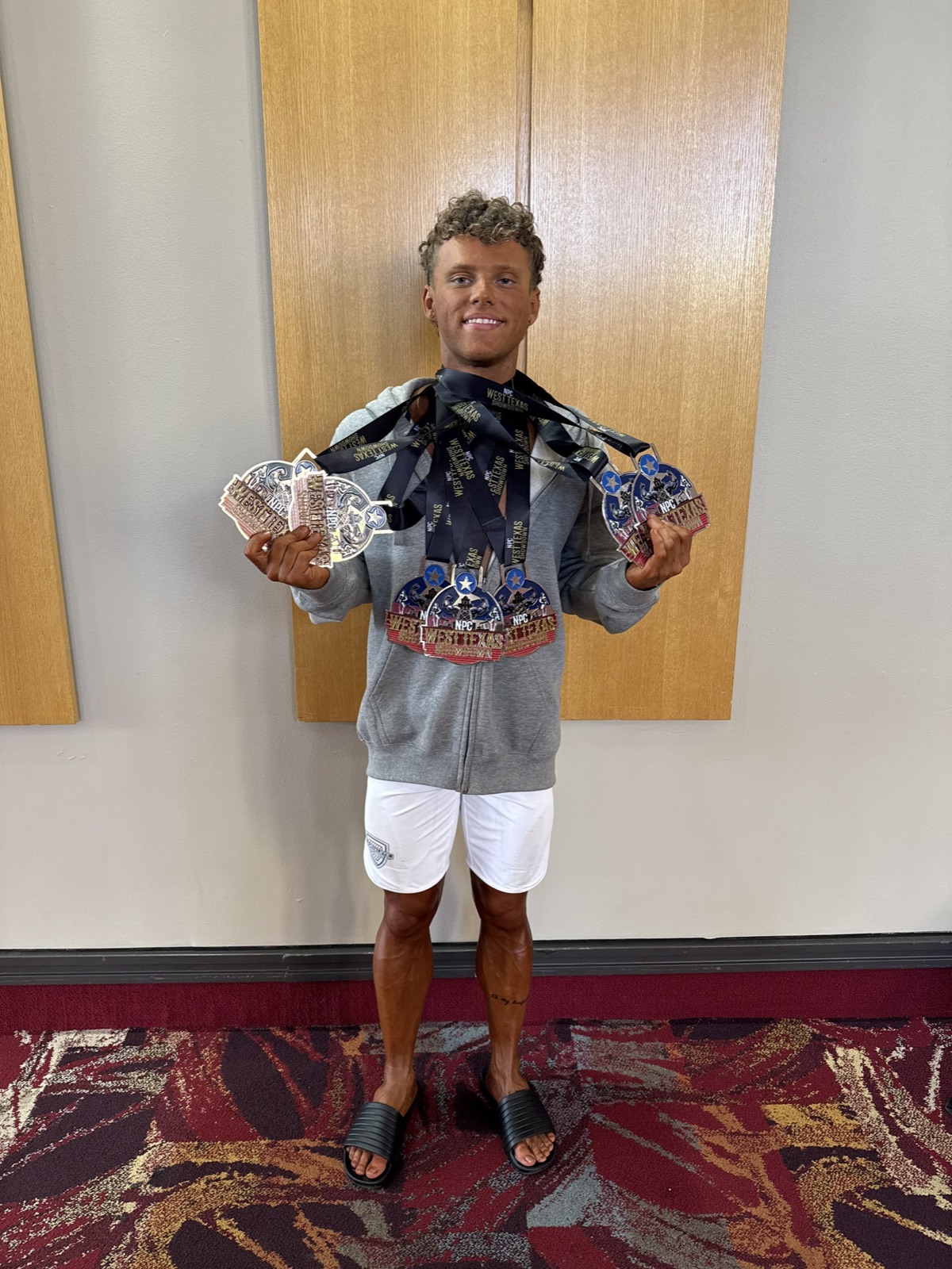 Bradyn Gamber holding a large collection of medals from the NPC West Texas Showdown.