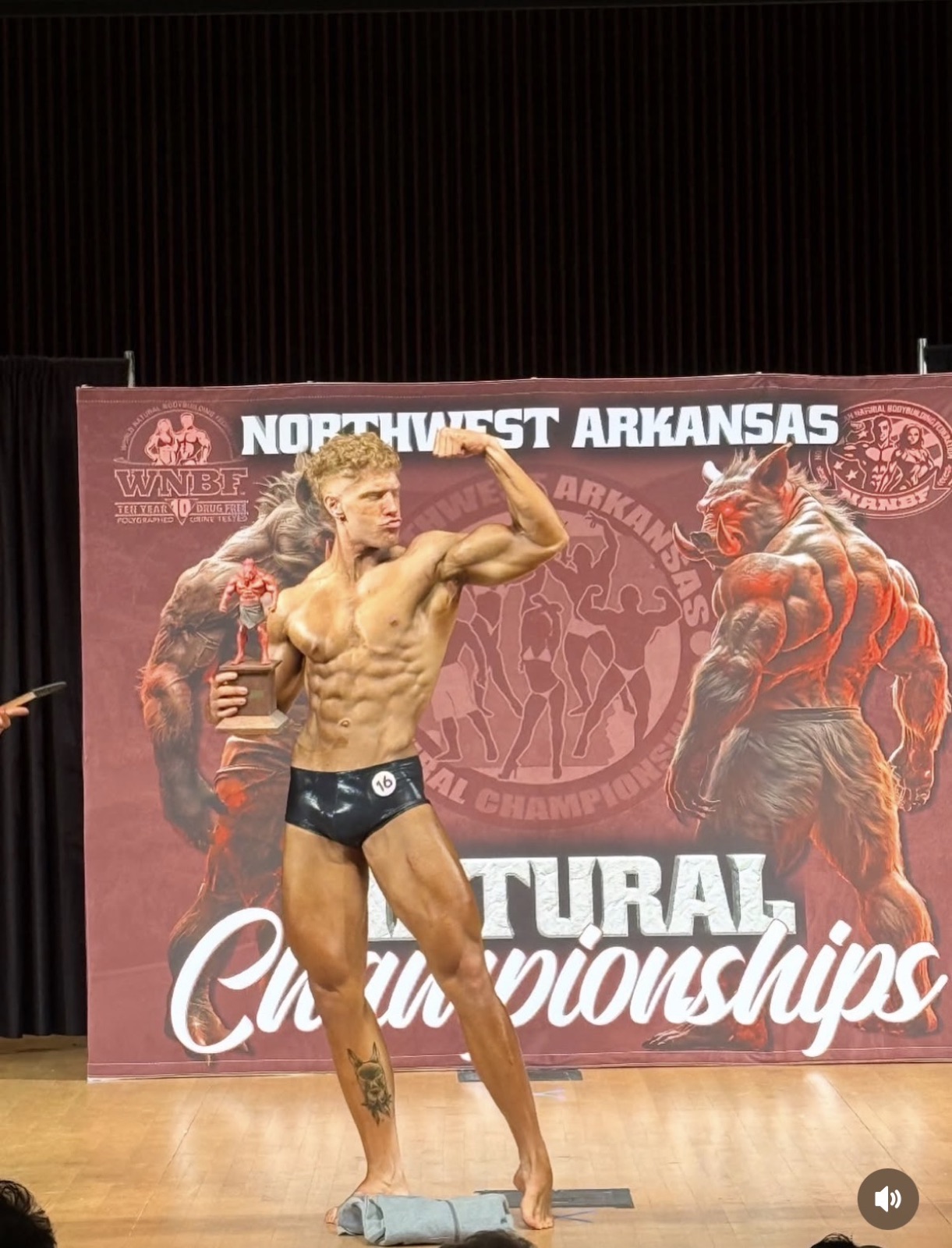 Client onstage at the WNBF Northwest Arkansas Natural Championships holding a trophy.