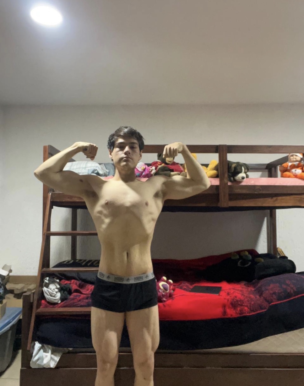 Young male client hitting a front double bicep pose showing lean muscle development.